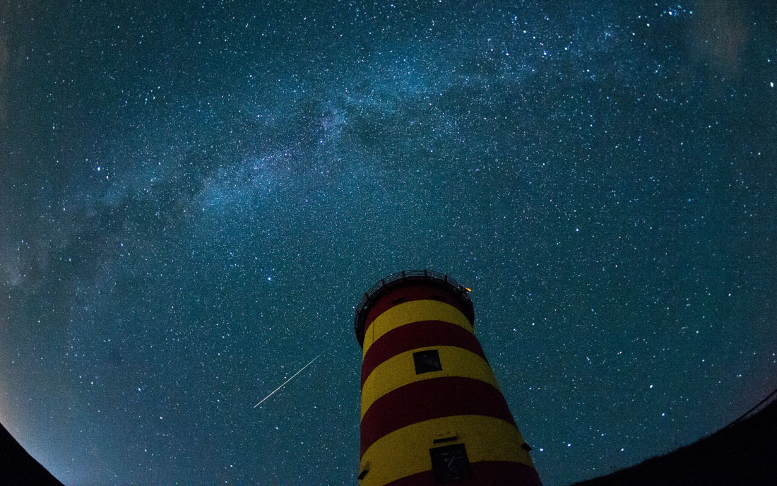 Pilsum, 13.08.2015: Eine Sternschnuppe am Nachthimmel über dem Pilsumer Leuchtturm ©dpa